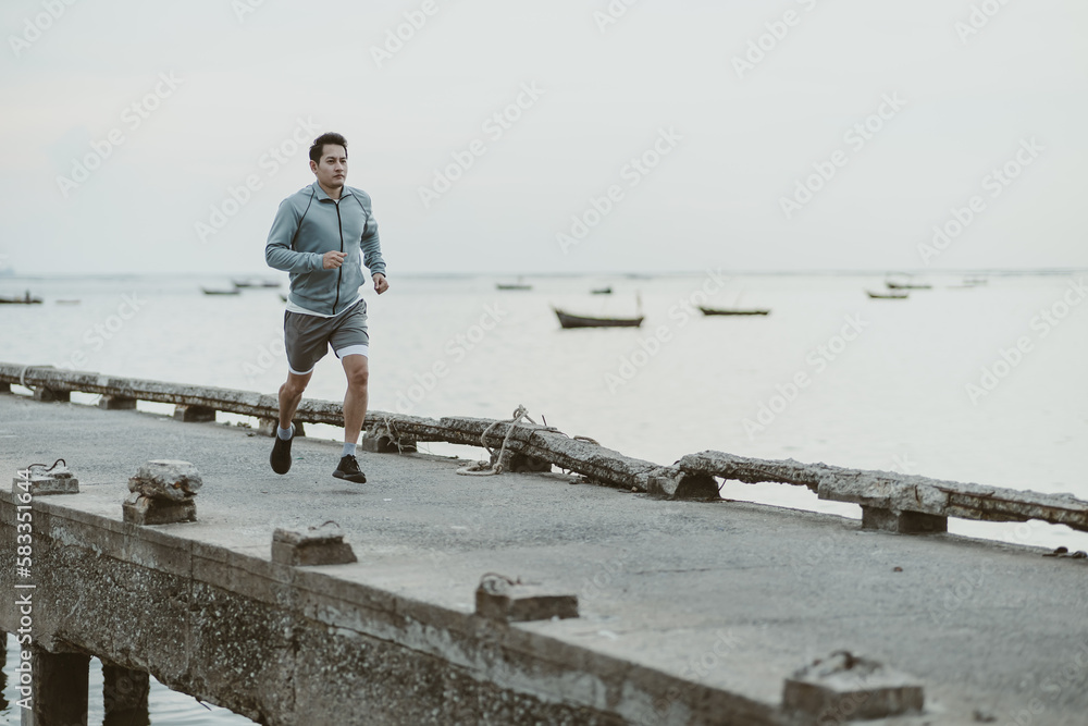 healthy lifestyle young fitness man running at seaside old bridge. Outdoor workout,  Healthy lifestyle concept.