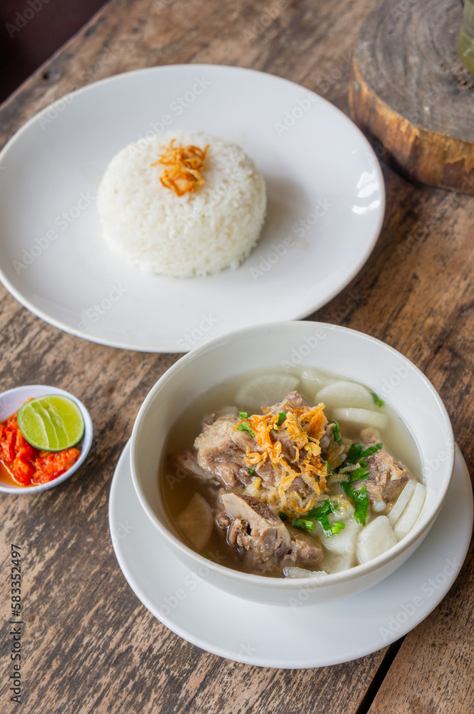 Delicious Pork Rib Soup or Soto Iga Babi Served with Chili Sauce or Sambal and Steam Rice Delicious Pork Rib Soup or Soto Iga Babi Served with Chili Sauce or Sambal and Steam Rice
