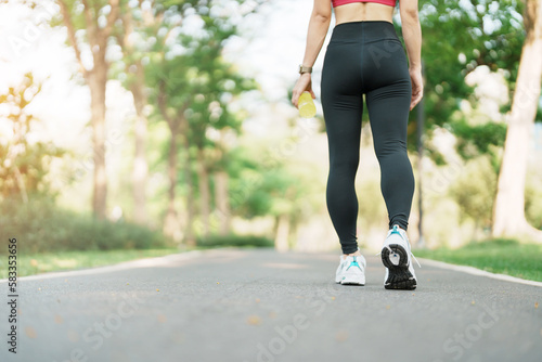 woman jogging and walking on the road at morning, Young adult female in sport shoes running in the park outside, leg muscles of Athlete. Exercise, wellness, healthy lifestyle and workout concepts