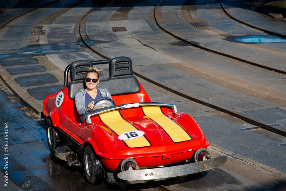 Cute Smiling woman driving a fun go cart ride at an outdoor amusement park. Enjoying a fun day playing on the rides at the park