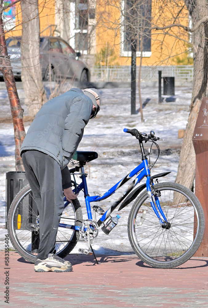 A man stands with a bicycle on a spring day