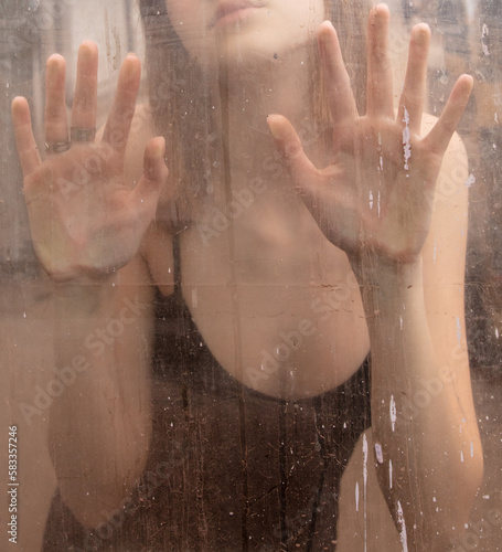 Girl's hands behind dirty glass