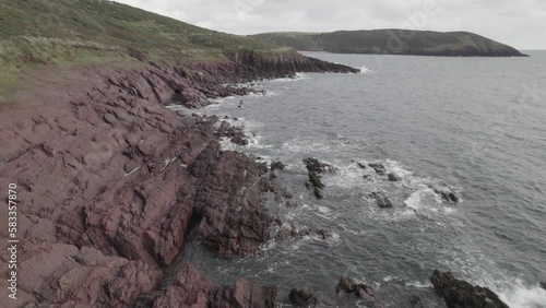 : Water washing coastal rocks, seaside landscape. Ascending footage of rugger sea coast. Blue Water, South Wales, UK photo