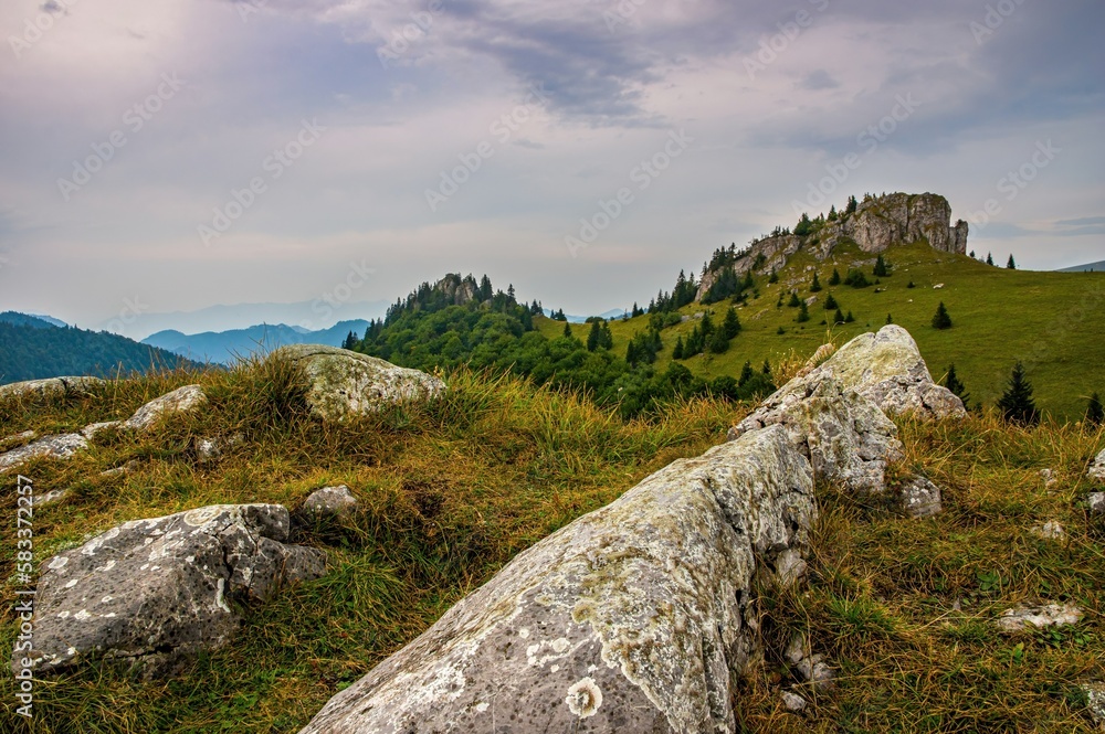 Panorama of mountain landscape with beautiful colorful sky, rocky cliff and mountain meadows with trees. Limestone peak named King's Well - Kralova studna, Greater Fatra National Park, Slovakia.