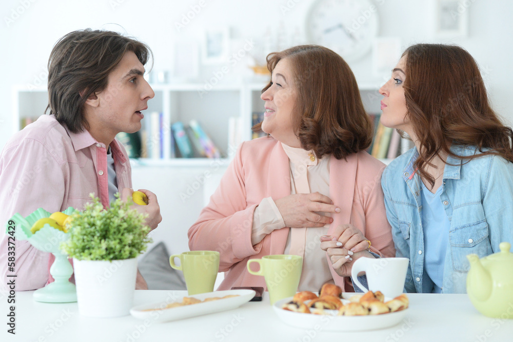 family of three spending time together at dinner table with cookies and tea