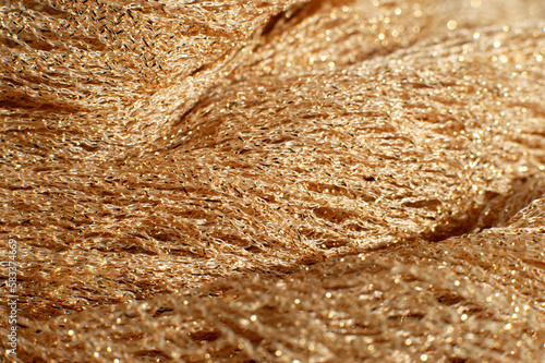 Cloth with glitter closeup. Fabric of golden color for sewing and decoration. Glitter textile creates the backdrop.