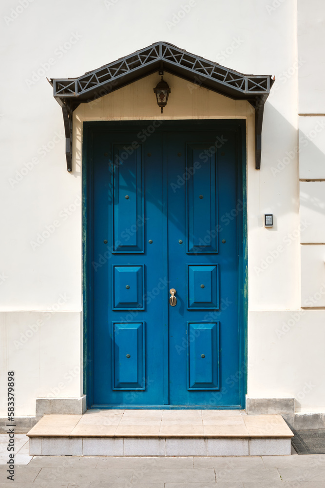 Beautiful blue wooden door against a white wall. Beautiful blue wooden door against a white wall.
