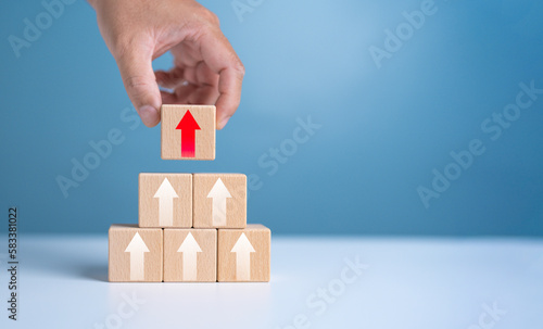Hand arranging wooden cube block stacking as step stair with arrow up. Business growth success process. Ladder career path for business growth success process concept. Flourish and Up Trend.