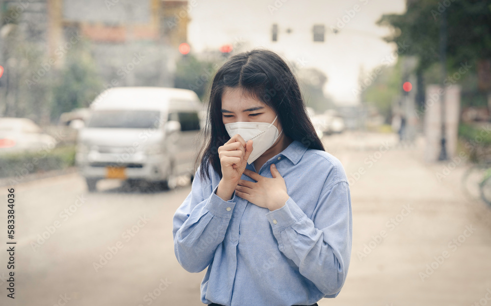 Asian woman wearing the N95 Respiratory Protection Mask against PM2.5 air pollution and headache Suffocate. City air pollution concept Asian woman wearing the N95 Respiratory Protection Mask against PM2.5 air pollution and headache Suffocate. City air pollution concept
