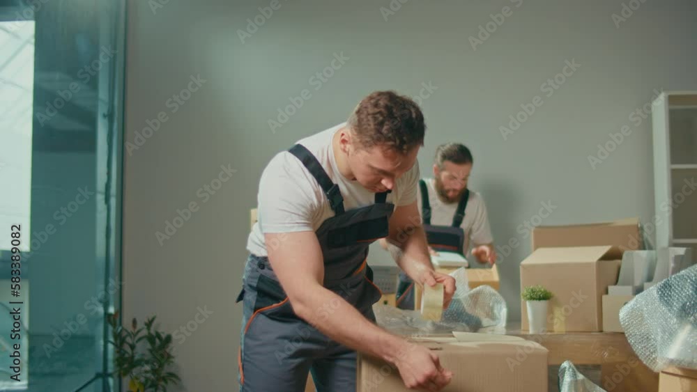 Employee Worker Sealing Cardboard Box Using Duct Tape Machine. Professional Packing and Unpacking Services. Packing and Preparation for Moving. Packing Supplies and Materials
