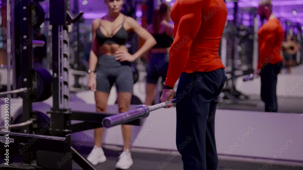 The bodybuilder trainer shows how to properly perform exercises on the simulator in the gym to a young pretty girl. Fitness training and an active lifestyle. The bodybuilder trainer shows how to properly perform exercises on the simulator in the gym to a young pretty girl. Fitness training and an active lifestyle.