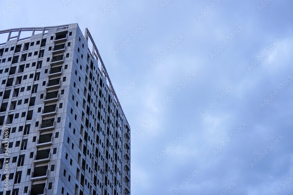 An unfinished building stands tall against a bleak grey sky, devoid of any signs of life or activity, with its empty spaces waiting to be filled An unfinished building stands tall against a bleak grey sky, devoid of any signs of life or activity, with its empty spaces waiting to be filled