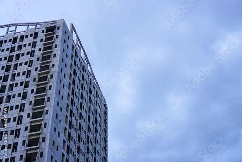 An unfinished building stands tall against a bleak grey sky, devoid of any signs of life or activity, with its empty spaces waiting to be filled