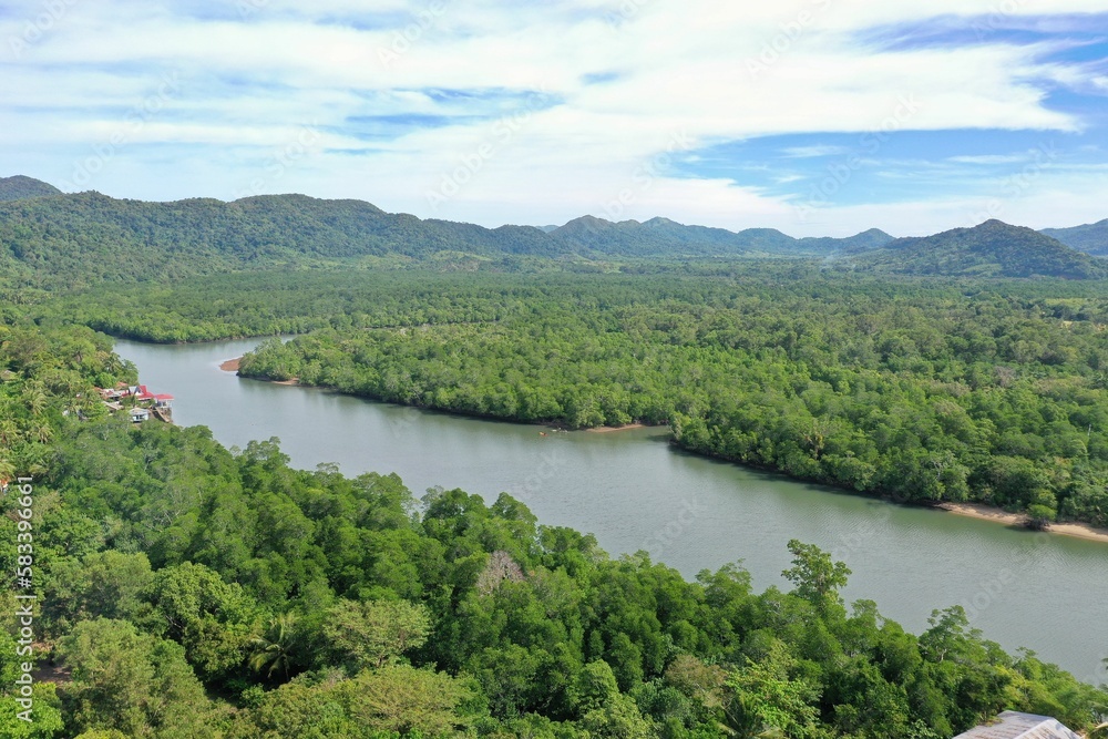 Panorama drone shot over the paradisiacal rainforest landscape of Coron in the Philippines with a river flowing through it and green hills in the background.