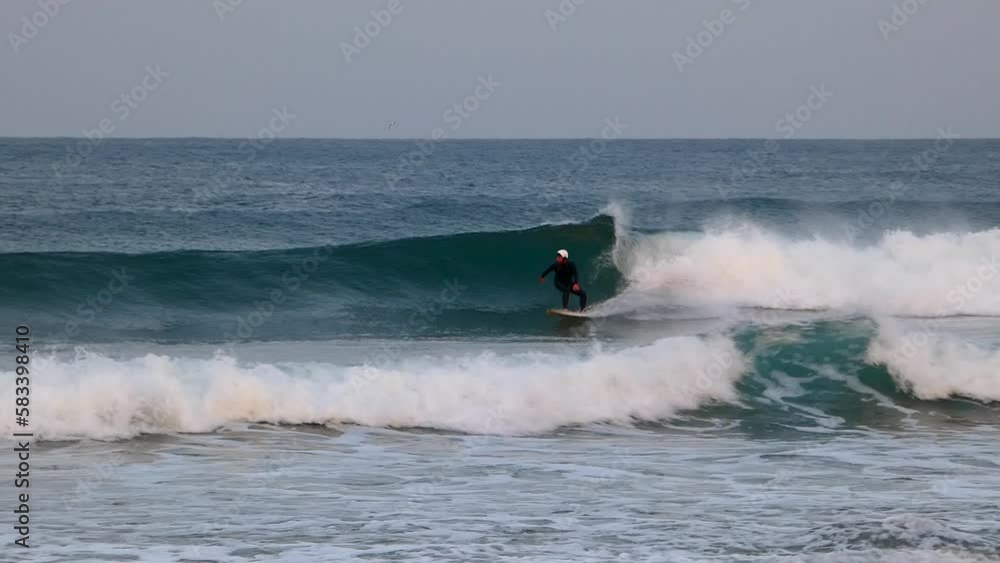 slow motion view of the surfer surfing in the ocean on Guincho beach. Guincho is famous for its beautiful beaches. Cascais. slow motion view of the surfer surfing in the ocean on Guincho beach. Guincho is famous for its beautiful beaches. Cascais.
