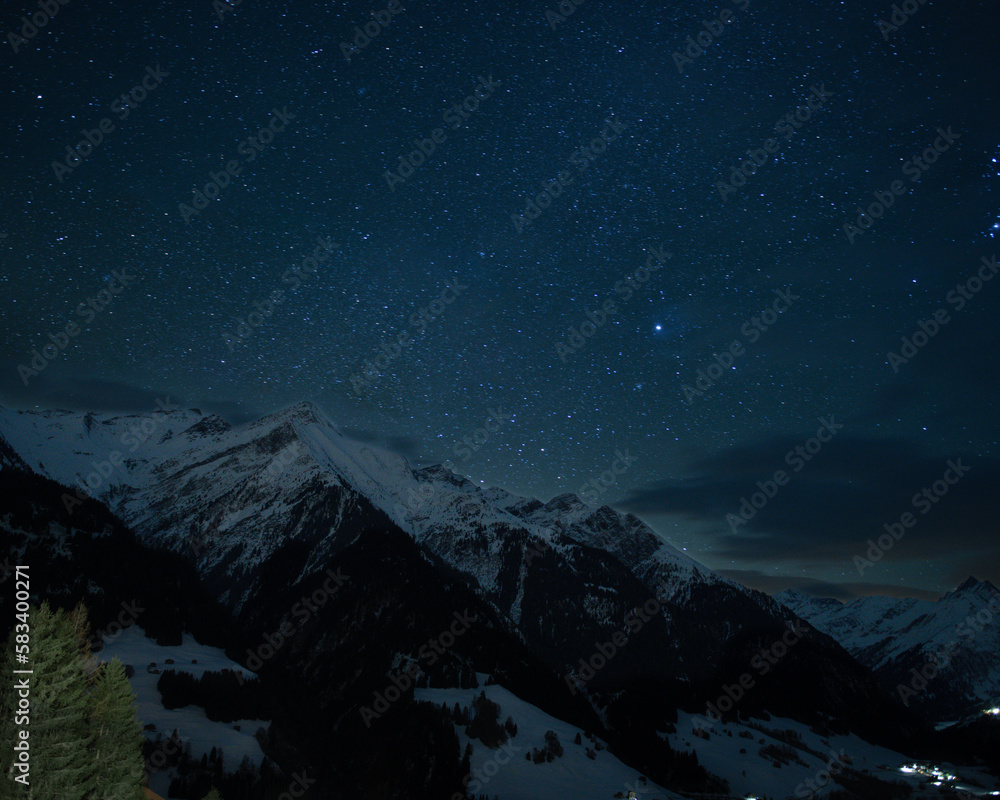 Snow covered mountain in Grisons, Swiss Alps, in long exposure is under starry sky.
