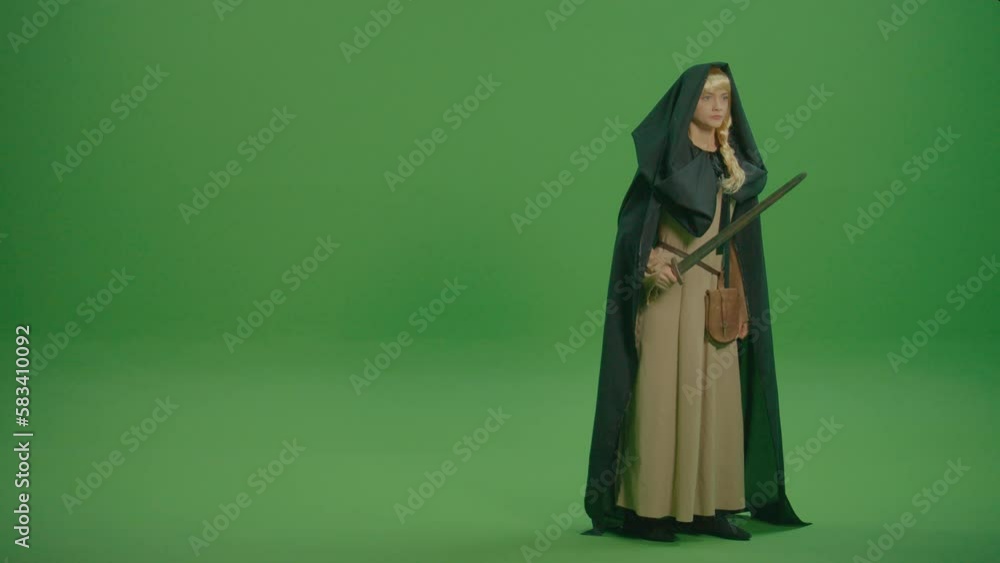 Green Screen. A Warrior Woman Dressed in a Medieval Dress and Cloak With a Hood Walks With a Sword in Her Hand. Mage Battles: Battles and Duels Between Spell Casters. Green Screen. A Warrior Woman Dressed in a Medieval Dress and Cloak With a Hood Walks With a Sword in Her Hand. Mage Battles: Battles and Duels Between Spell Casters.