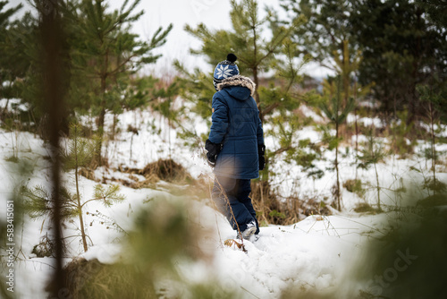 Boy walking in winter forest alone.