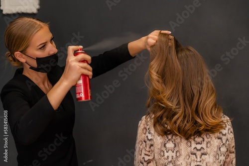 Women salon hairstyle. Hairdresser uses hairspray on client's hair in salon, Portrait of two beautiful women © svetograph