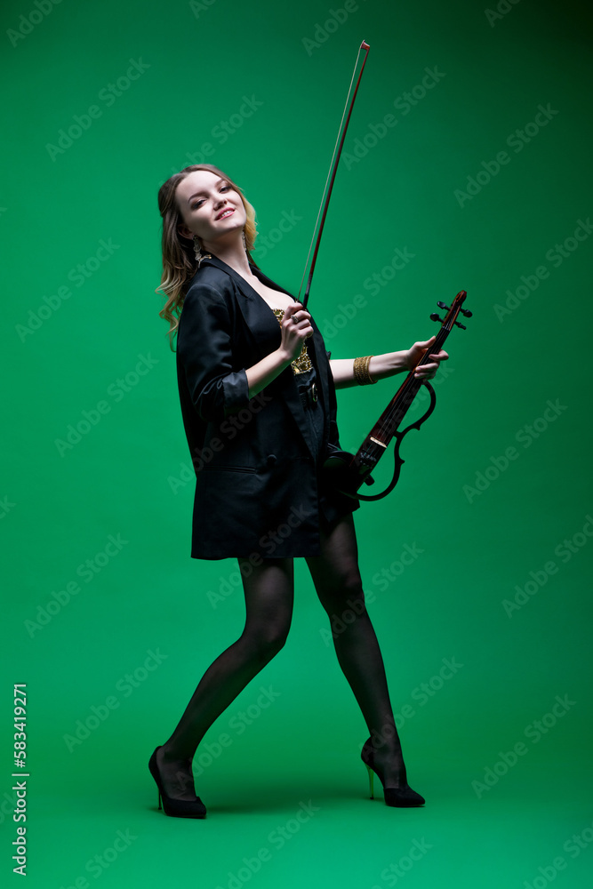 Violinist woman in the black blazer on the green background.