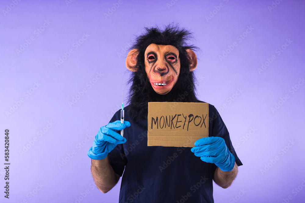 Person dressed in a monkey with a mask, with a medical nurse's suit, with a sign that reads: MONKEYPOX, and a syringe, on a purple background. Pandemic, virus, epidemic, Nigeria and smallpox concept.