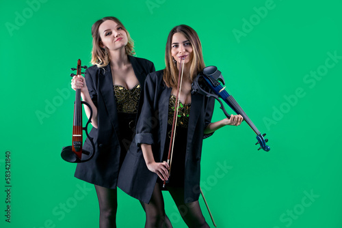 Tableau sur toile Violinist women duet in the black blazers on the green background