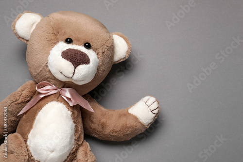 Cute teddy bear on gray background, top view. Space for text
