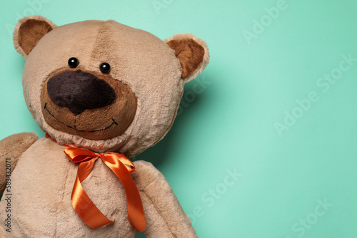 Cute teddy bear on turquoise background, top view. Space for text
