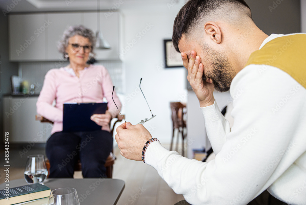 Senior female psychologist talking to man during therapy.