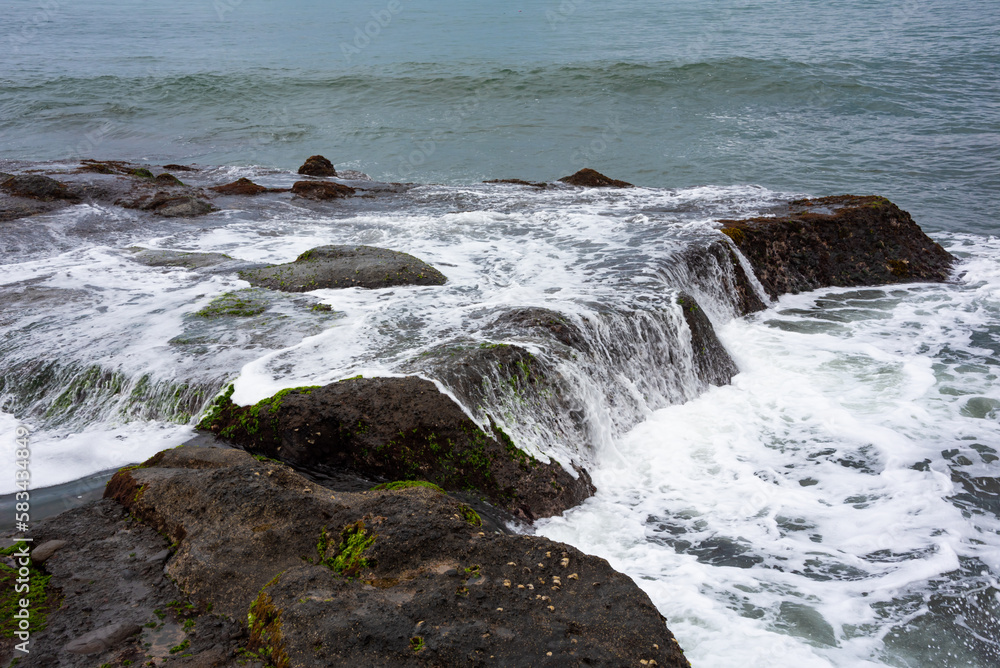 Rocky sea coast hit by waves on Bali island