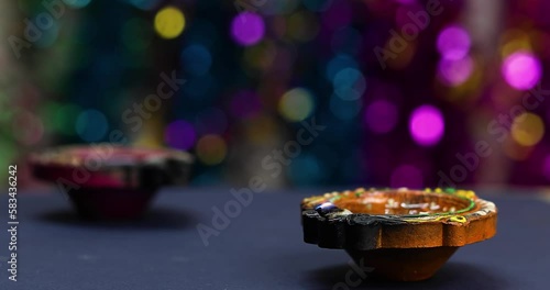 Diwali diya oil lamp extinguished in air with colorful bokeh light effects background.