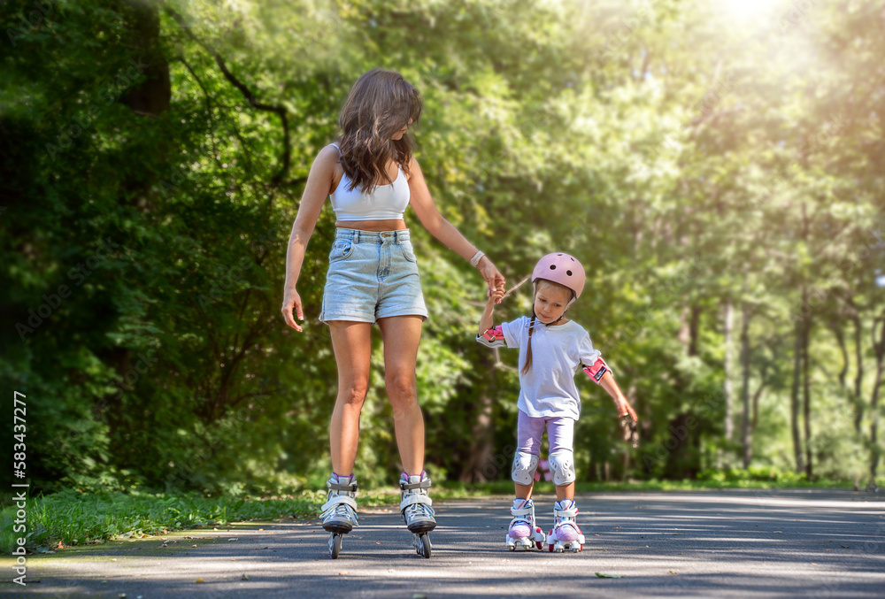 Mother teaching child daughter to skate on inline skates rollers in public park in summer. Family leisure outdoor sport activity game. Copy negative space Mother teaching child daughter to skate on inline skates rollers in public park in summer. Family leisure outdoor sport activity game. Copy negative space