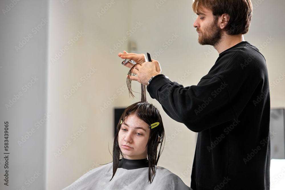 Fototapeta premium Professional male hairdresser cutting female hair in salon