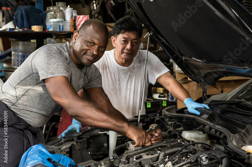 Black Car Mechanic working with Asian mechanic in auto repair garage 