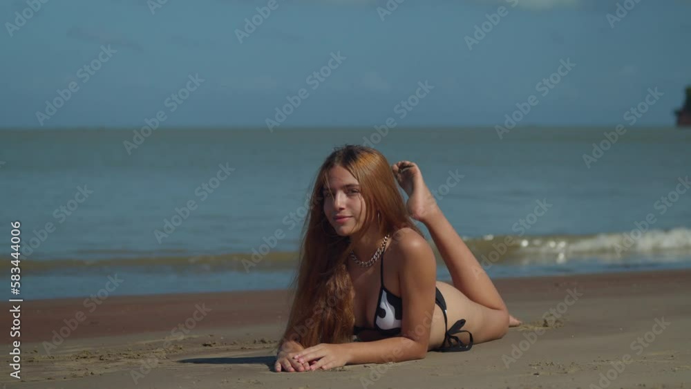 Brunette latina laying in the sand of a tropical beach with ocean waves in the background Brunette latina laying in the sand of a tropical beach with ocean waves in the background