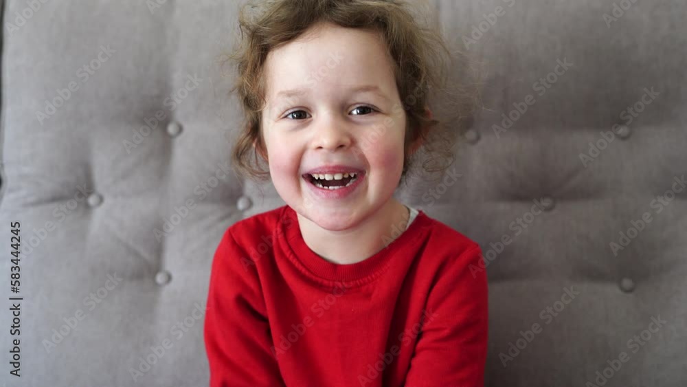 Close-up Portrait of Happy Little Child Girl Bursting in Laugh. Kid Laughs Indoors at home. Looking to Camera Close-up Portrait of Happy Little Child Girl Bursting in Laugh. Kid Laughs Indoors at home. Looking to Camera