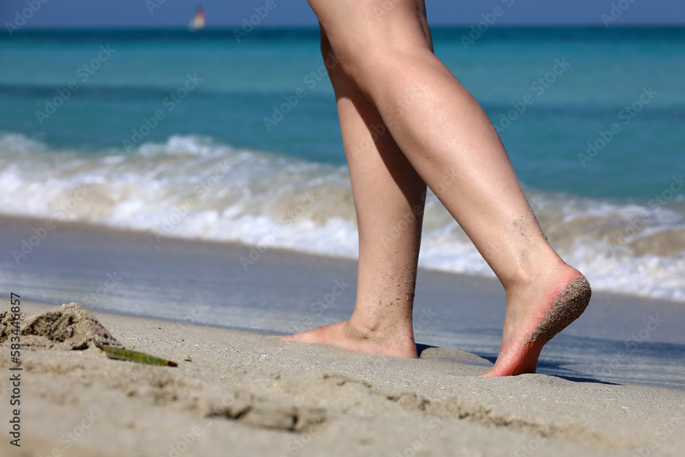 Barefoot woman walking by sea waves. Female legs on a sand, beach vacation and workout Barefoot woman walking by sea waves. Female legs on a sand, beach vacation and workout