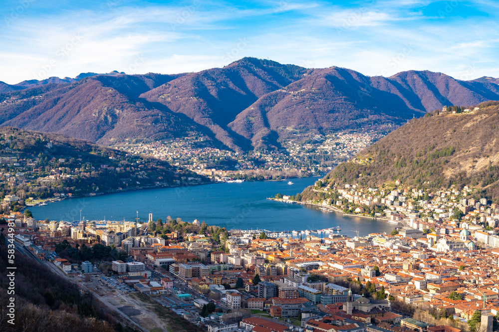 The city of Como, the lake, the lakeside promenade, the buildings, photographed from above.
