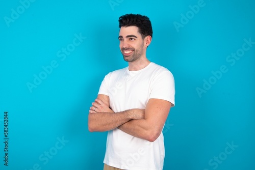 Young man wearing white T-shirt over blue studio background cross hands look copy space