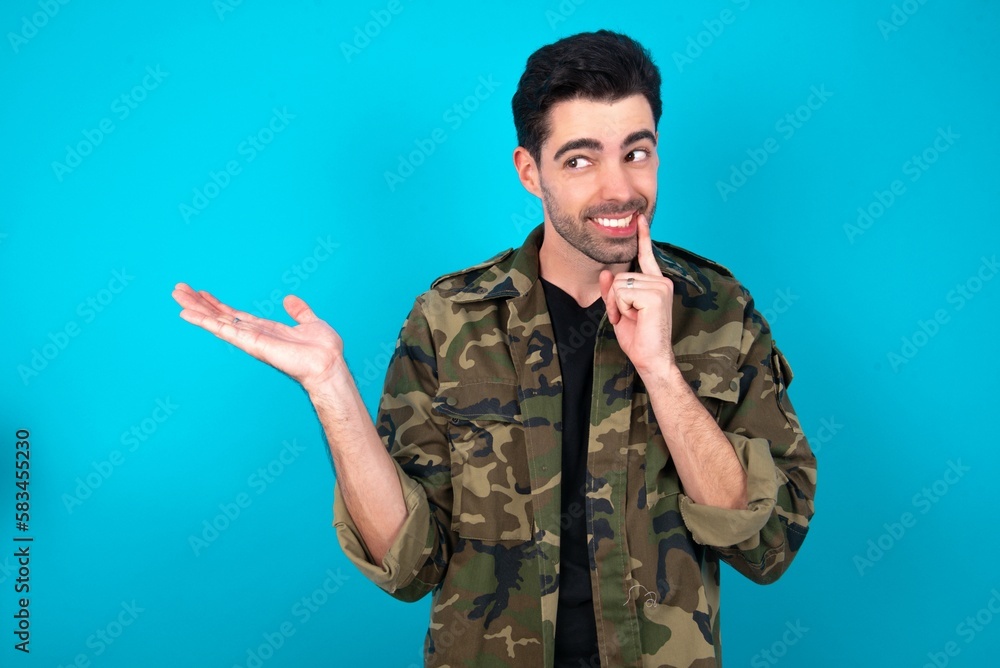 Positive Young man standing over blue studio background advert promo touch finger teeth Positive Young man standing over blue studio background advert promo touch finger teeth