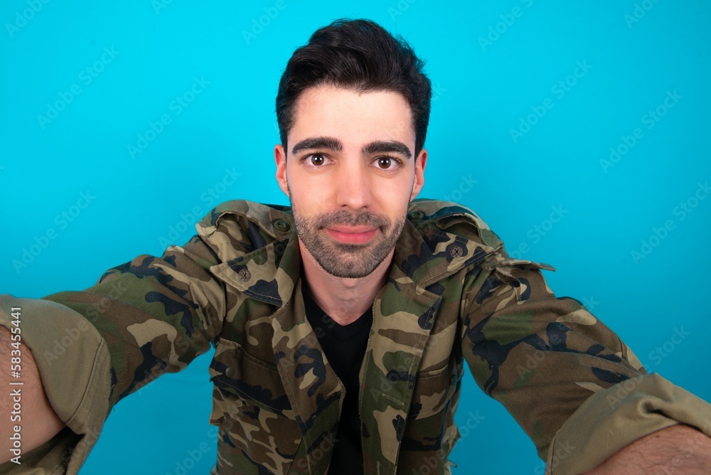 Photo of Young man standing over blue studio background do selfie