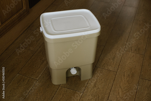 Trash bin for composting from kitchen at home on the floor. Copy space. Recycling organic scarps concept. Sustainable, ecology, zero waste lifestyle