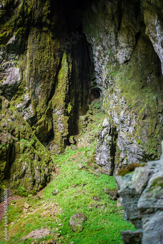 shady steep gorge with a lake and an entrance to a cave complex Macocha