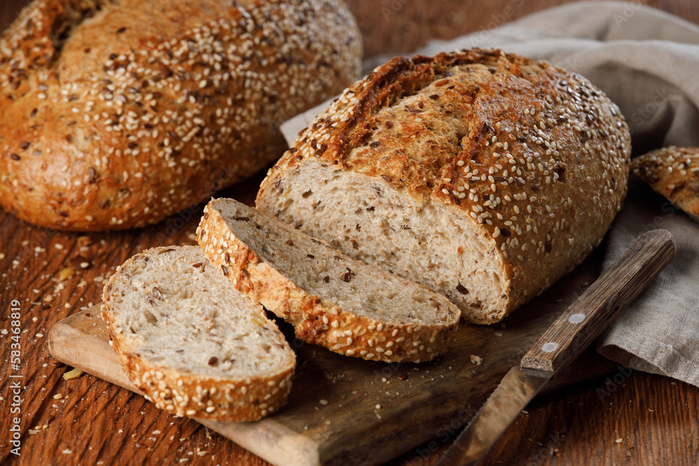 Rustic whole grain bread on a cutting board on a wooden kitchen table Rustic whole grain bread on a cutting board on a wooden kitchen table