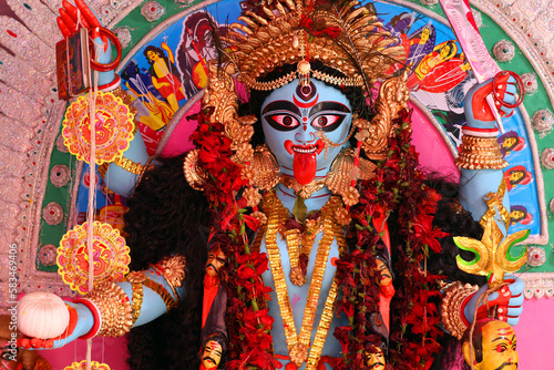 The terrible goddess Kali with her tongue hanging out and a severed head in her hands. Traditional Hindu altar in West Bengal.