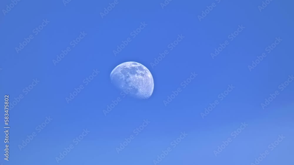 Daytime moon on blue sky with light haze and atmospheric distortion Daytime moon on blue sky with light haze and atmospheric distortion