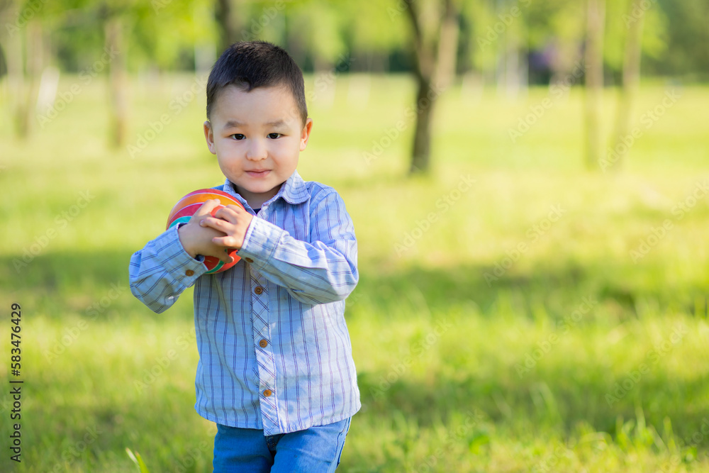asian boy holding soccer ball, playing football on sunny day outdoor. Kazakh child daylight saving time. Future champion. portrait, copy space, text asian boy holding soccer ball, playing football on sunny day outdoor. Kazakh child daylight saving time. Future champion. portrait, copy space, text