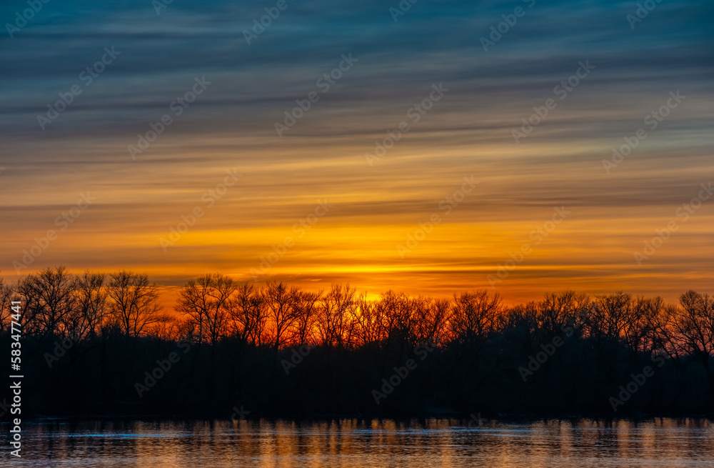 Color gradants in sunset sky over forest and water. Natural beautiful evening landscape