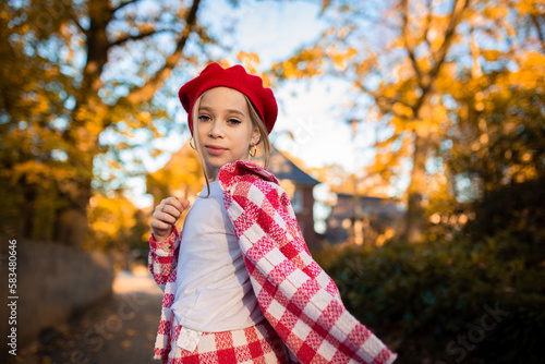 A girl in a red biret against the background of golden autumn. Beautiful portrait of a girl in a red biret.