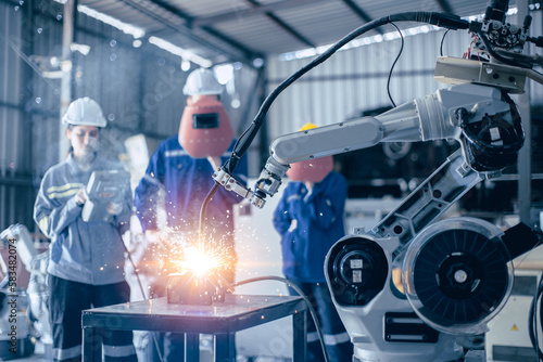 Engineer worker team working control operate small robot welding arm in metal workshop